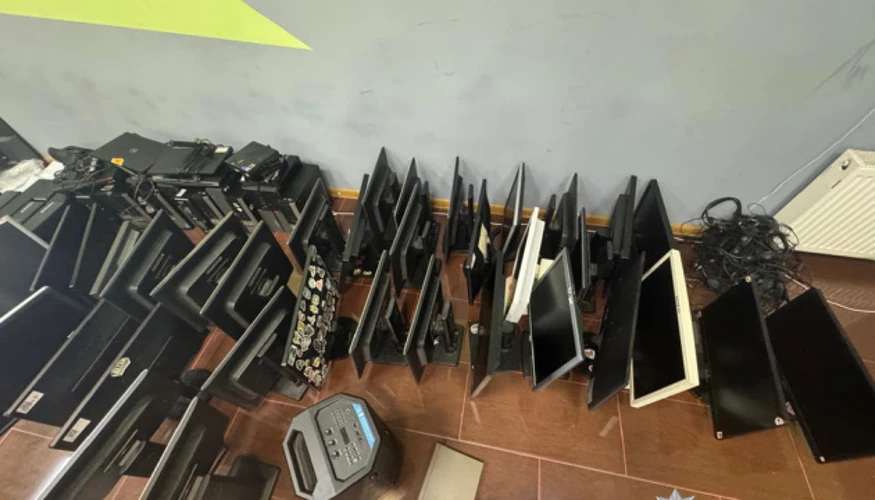 Правоохоронці під час обшуку шахрайського кол-центру поряд із вилученими комп’ютерами, телефонами, SIM-картками та готівкою.